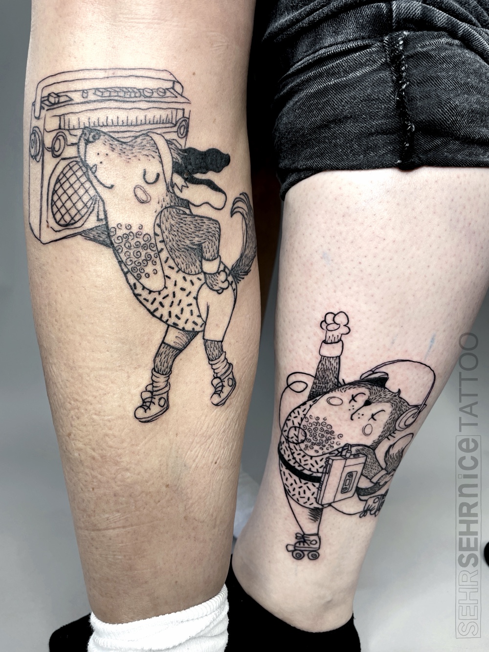 Freundschaftstattoo mit Hund und Katze in 80er-Jahre-Sportoutfits und Boombox in Schwarz-Grau
