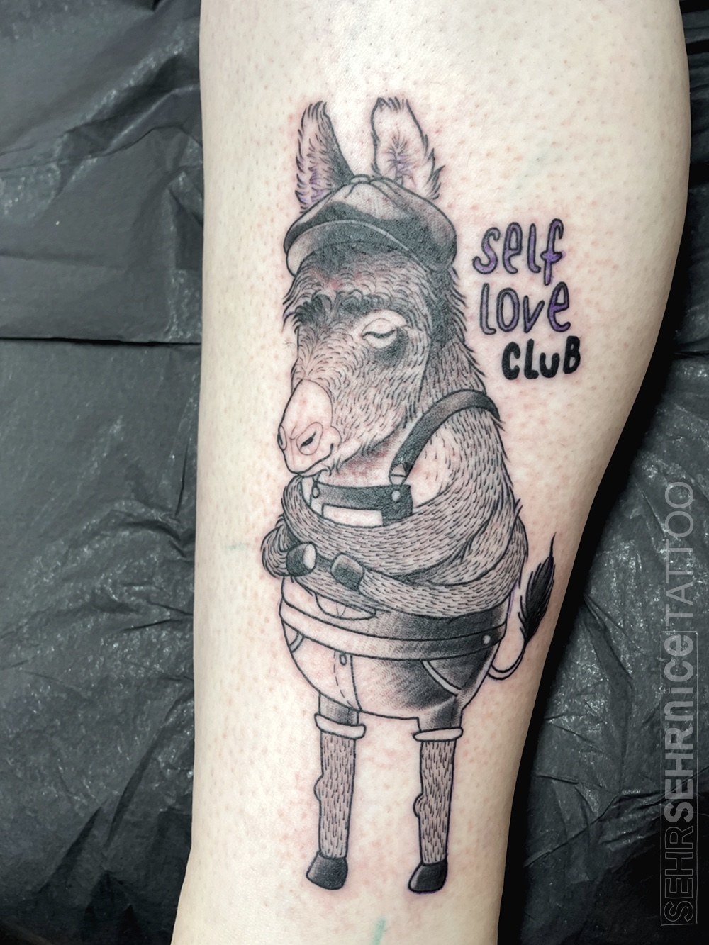 Esel Tattoo mit Schriftzug „self love club“ in Schwarz-Grau