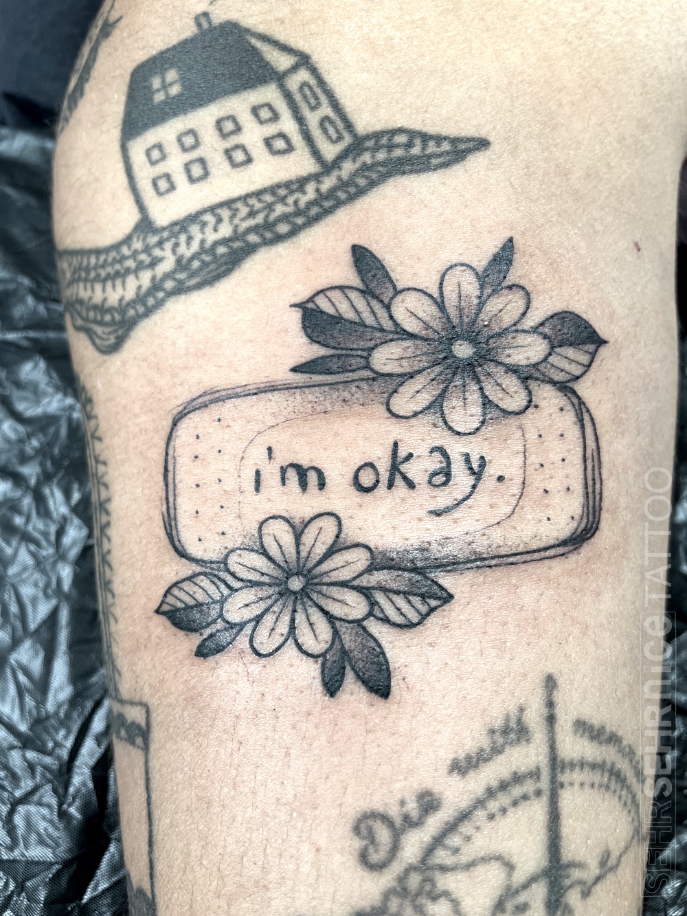 Pflaster Tattoo mit Blumen und Schriftzug „i’m okay“ in Schwarz-Grau